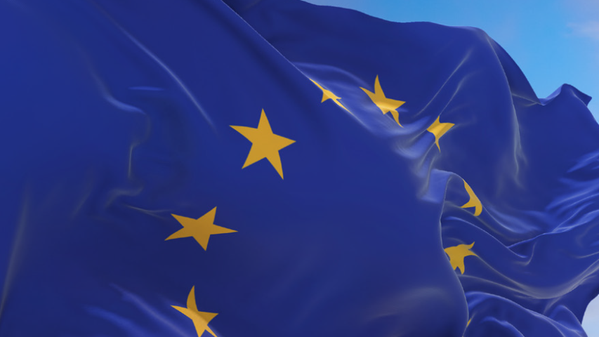 Powiewająca flaga Unii Europejskiej na tle wieczornego, lekko zachmurzonego nieba